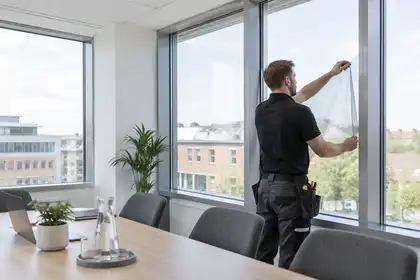 Installer finishing clear window film in a meeting room