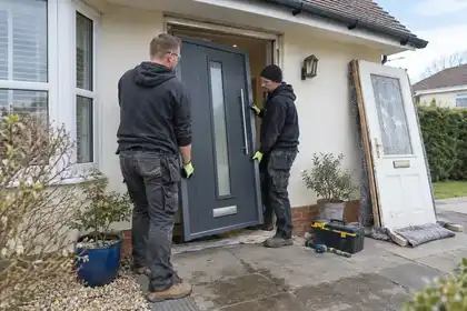 Two fitters positioning a composite front door in its opening